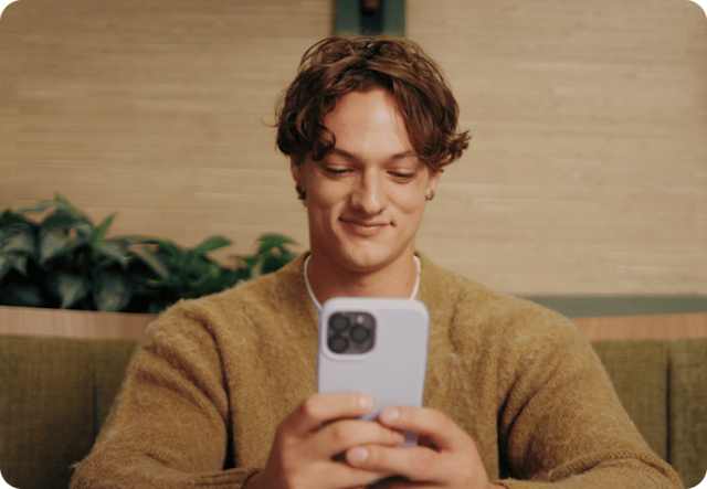 Image of person in brown sweater looking down at mobile phone in gray case with at SMS text message they received from business using Mailchimp SMS features.